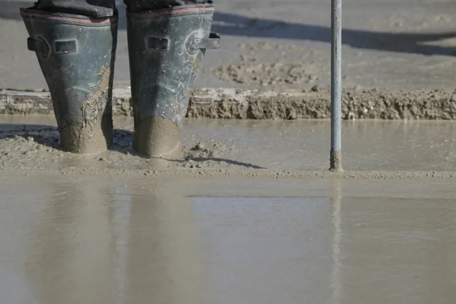 Wet cement slurry being worked across a concrete surface with a hand trowel