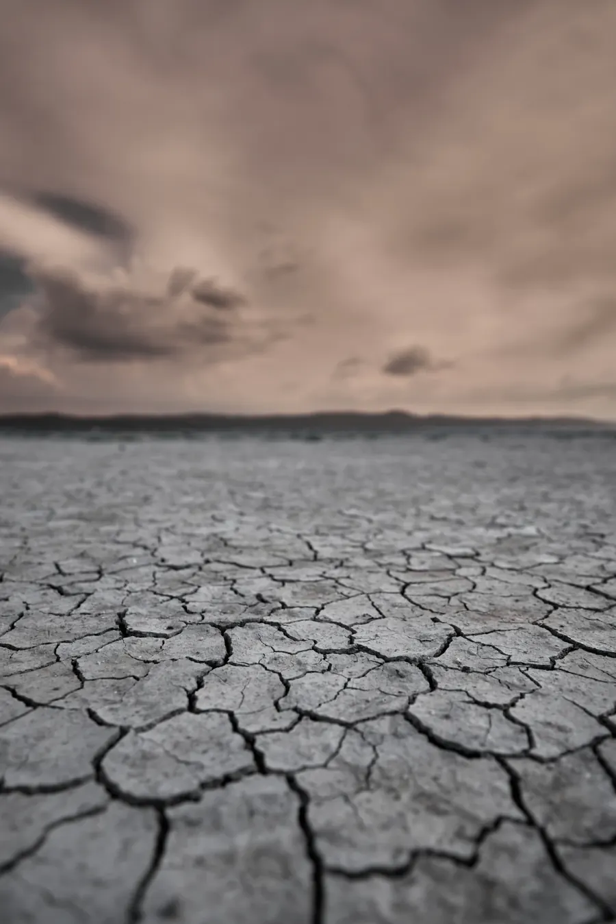 Wide dry cracked lakebed stretching to the horizon under a stormy sky